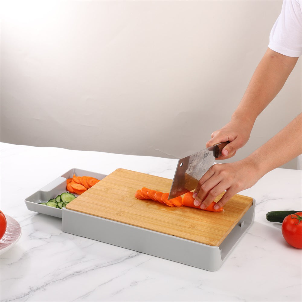 Person cutting vegetables on a wooden cutting board with a gray tray underneath.